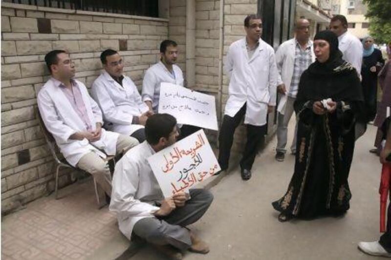 Doctors  on strike demanding a raise in their salaries, better working conditions, and improved services at the country's hospitals. The Arabic reads 'Doctors deserve the high salaries category.'