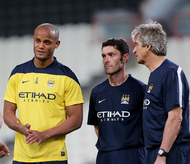 Manchester City captain Vincent Kompany, left, talks with manager Manuel Pellegrini, right, during Wednesday night's training session in Abu Dhabi. Satish Kumar / The National / May 14, 2014