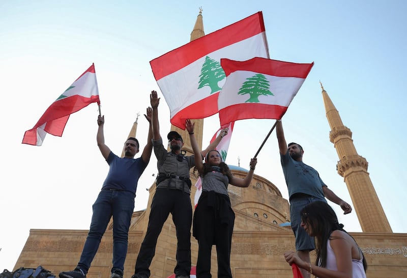 Demonstrators hold the national flags during an anti-government protest in downtown Beirut, Lebanon October 21, 2019. REUTERS/Ali Hashisho