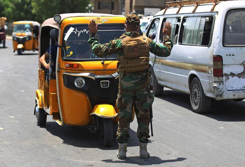 A Iraqi soldier stops a tuk-tuk at a checkpoint to ensure compliance with the rules in Baghdad's Sadr City on June 3, 2020 amid a curfew imposed to curb the latest increase in coronavirus cases.  / AFP / AHMAD AL-RUBAYE
