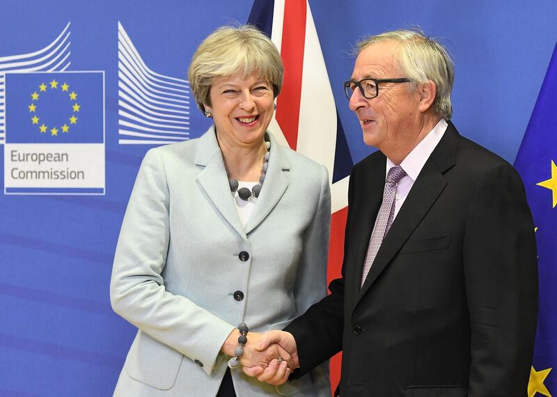 TOPSHOT - British Prime Minister Theresa May (L) is welcomed by European Commission Jean-Claude Juncker at European Commission in Brussels on December 8, 2017. / AFP PHOTO / EMMANUEL DUNAND