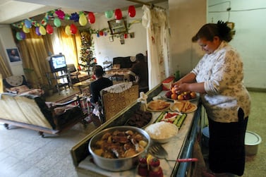 An Iraqi lady prepares a New Year's Eve meal in her kitchen as other family members watch television in the living room, at their home in an apartment block in the Al Sadun district of Baghdad, 31 December 2005. Ahmad Al-Rubaye / AFP 