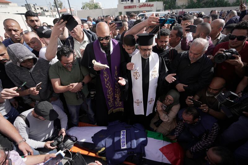 Journalists surround the body in mourning. AP