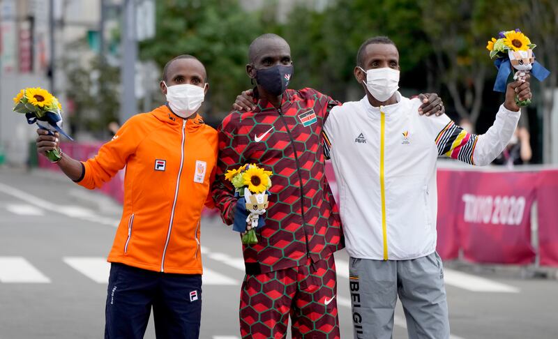Gold medalist Eliud Kipchoge of Kenya is joined by silver medalist Abdi Nageeye, left, of the Netherlands and bronze medalist Bashir Abdin of Belgium during the flower ceremony.