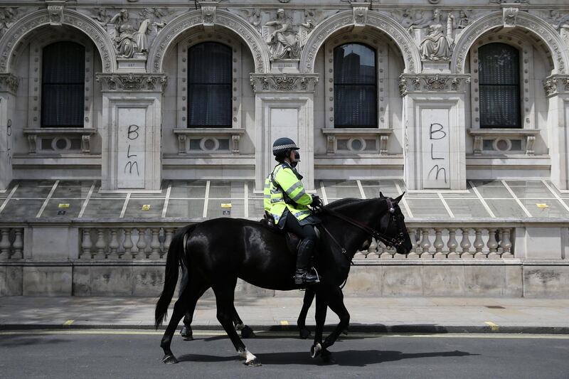 Mounted police pass graffiti written on the Foreign and Commonwealth Office in central London.  AFP