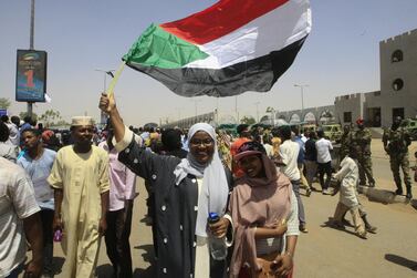 Sudanese women wave a national flag as they rally to celebrate after an announcement made by Sudan's new military ruler, General Abdel Fattah al-Burhan. AFP