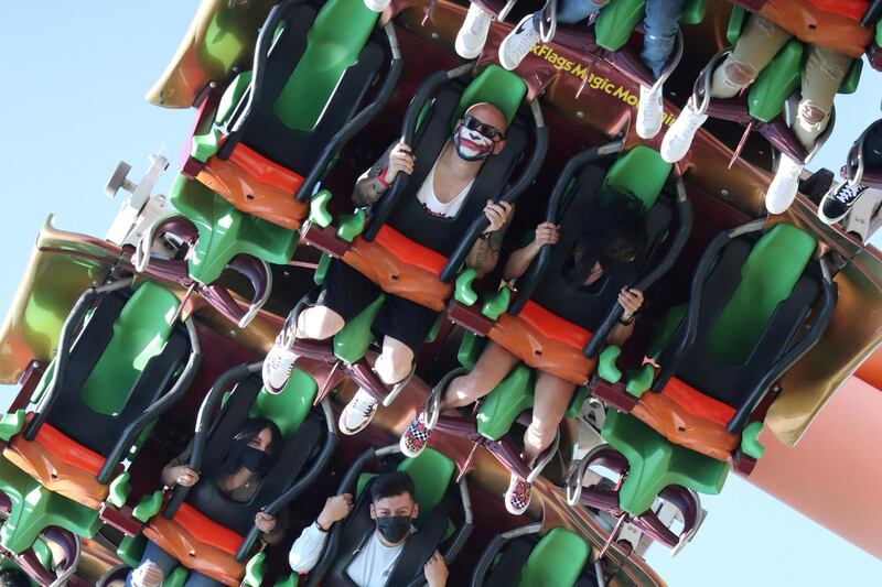People ride a roller coaster at Six Flags Magic Mountain amusement park on the first day of opening, as the coronavirus disease (COVID-19) continues, in Valencia, California, U.S. REUTERS