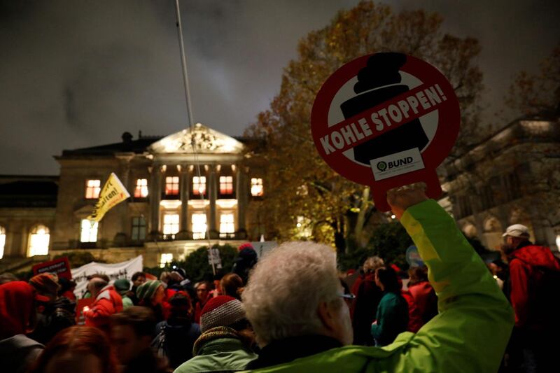 A protester holds a placard reading "stop coal" during a rally in front of the building of the German Parliamentarian Society that houses the exploratory talks of members of potential coalition parties to form a new government on November 16, 2017 in Berlin. / AFP PHOTO / Odd ANDERSEN