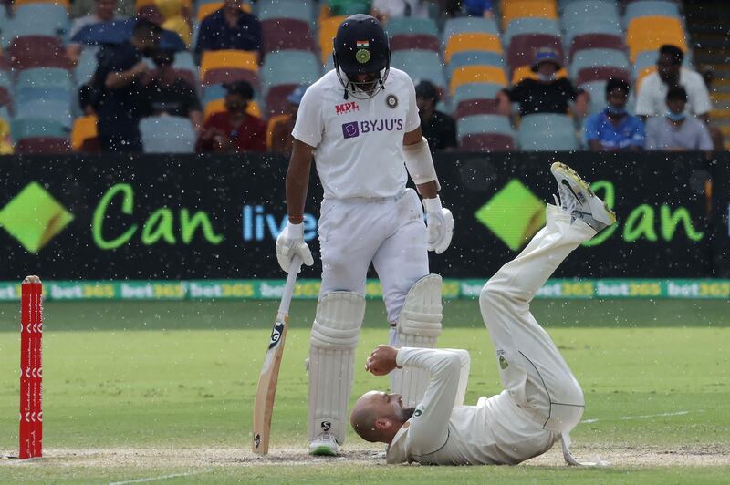 Australia's Nathan Lyon dives to grab the ball as India's batsman Cheteshwar Pujara looks on. AFP