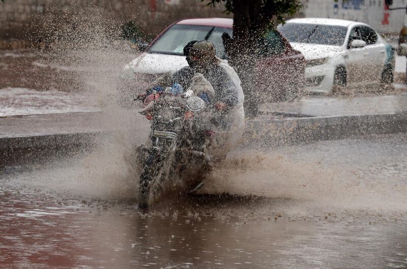Yemenis ride a motorcycle through a flooded street following heavy rains in Sana'a, Yemen.  EPA