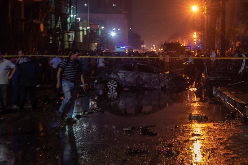 People surrounding a burned car after the explosion in downtown Cairo. AFP