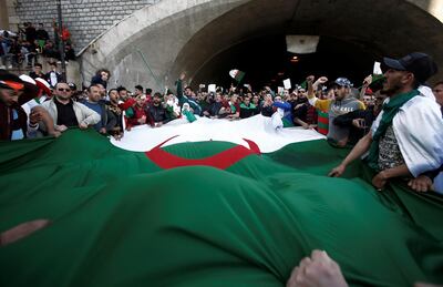 People carry a giant national flag as they protest over President Abdelaziz Bouteflika's decision to postpone elections and extend his fourth term in office, in Algiers, Algeria March 15, 2019.REUTERS/Ramzi Boudina