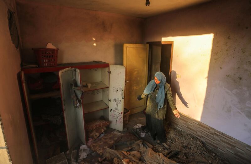 A Palestinian woman inspects the damage at her house after the strike. Mahmud Hams / AFP Photo.