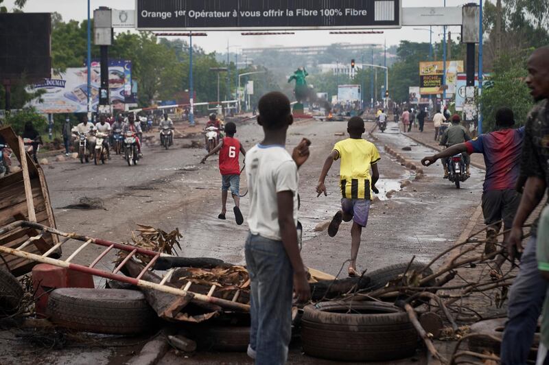 People run away at the arrival of the riot police as protesters set barricades to block the circulation on the Martyrs bridge of Bamako.  AFP