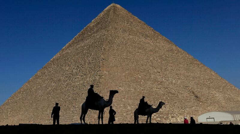 FILE - In this Dec. 12, 2012 file photo, policemen are silhouetted against the Great Pyramid in Giza, Egypt. Scientists have found a previously undiscovered hidden chamber in Egypt's Great Pyramid of Giza, the first such discovery in the structure since the 19th century. In a report published in the journal Nature on Thursday, Nov. 2, 2017, an international team says the 30-meter (yard) void deep within the pyramid is situated above the Grand Gallery, and has a similar cross-section. (AP Photo/Hassan Ammar, File)