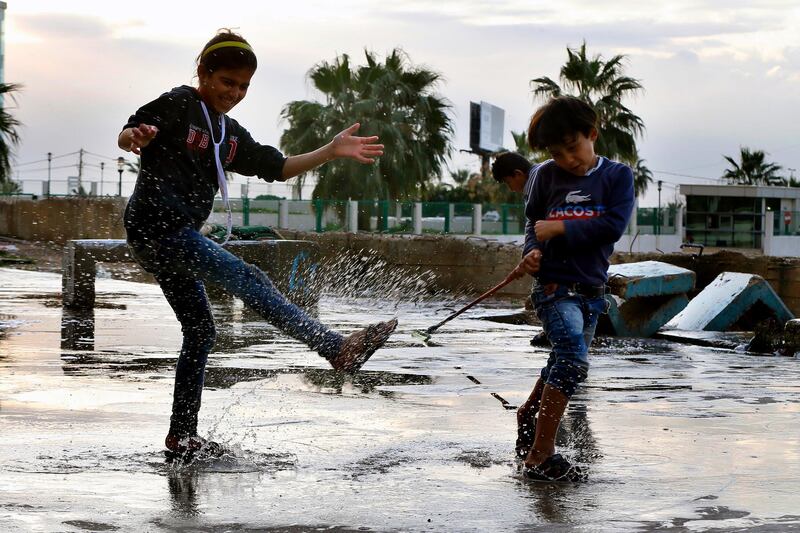 Children play in rainwater in a refugee settlement in Sidon, Lebanon. AP Photo