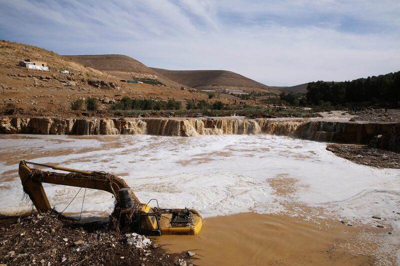 An excavator is partially submerged in a stream emergency personnel look for the missing. Reuters