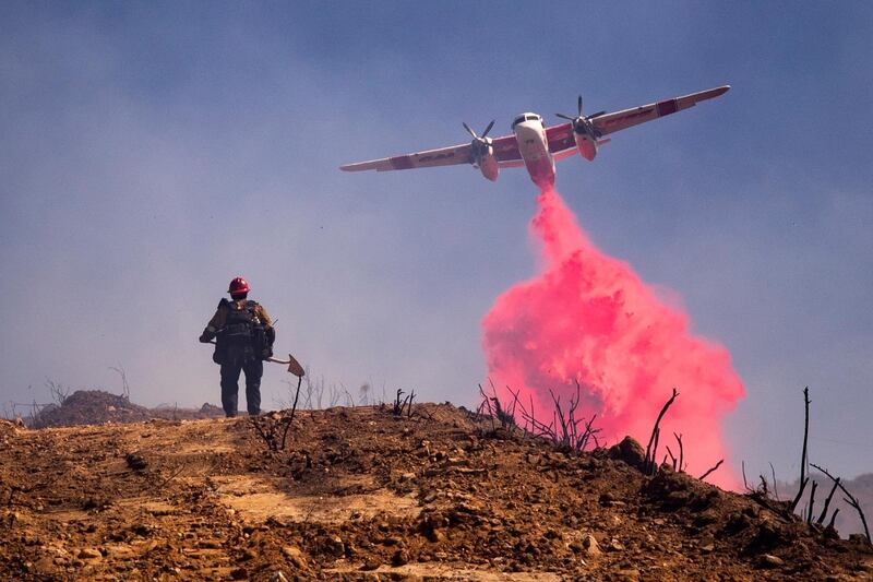 A plane flies over a fire fighter and drops retardant on the Elsmere Fire near Santa Clarita, California, USA.  EPA