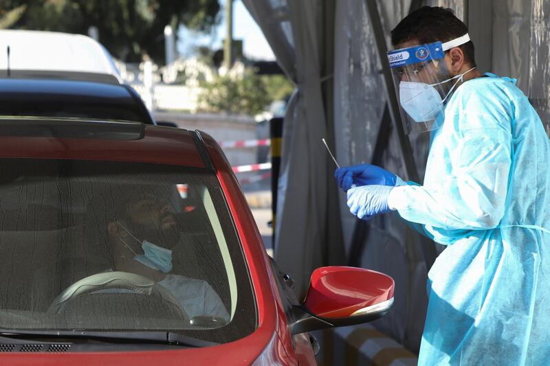 A healthcare worker takes a man's nasal swab sample as he checks for the coronavirus disease (COVID-19) at a drive-thru testing station in Amman, Jordan. REUTERS