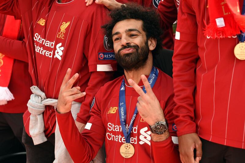 Liverpool's Egyptian midfielder Mohamed Salah gestures to the fans during an open-top bus parade around Liverpool, north-west England on June 2, 2019, after winning the UEFA Champions League final football match between Liverpool and Tottenham. Liverpool's celebrations stretched long into the night after they became six-time European champions with goals from Mohamed Salah and Divock Origi to beat Tottenham -- and the party was set to move to England on Sunday where tens of thousands of fans awaited the team's return. The 2-0 win in the sweltering Metropolitano Stadium delivered a first trophy in seven years for Liverpool, and -- finally -- a first win in seven finals for coach Jurgen Klopp. / AFP / Oli SCARFF                          
