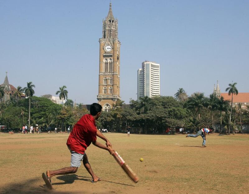 Residents of Mumbai play cricket as the Bombay Stock Exchange building is seen in the background (AP Photo/Rajesh Nirgude)