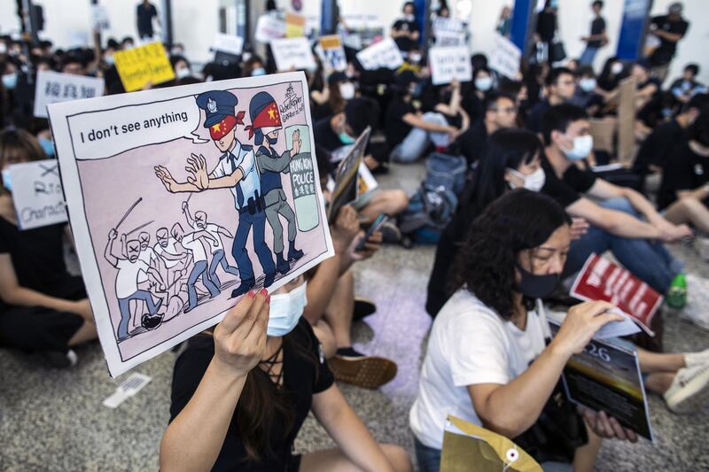 A demonstrator holds a placard featuring an illustration criticising Hong Kong police. Bloomberg