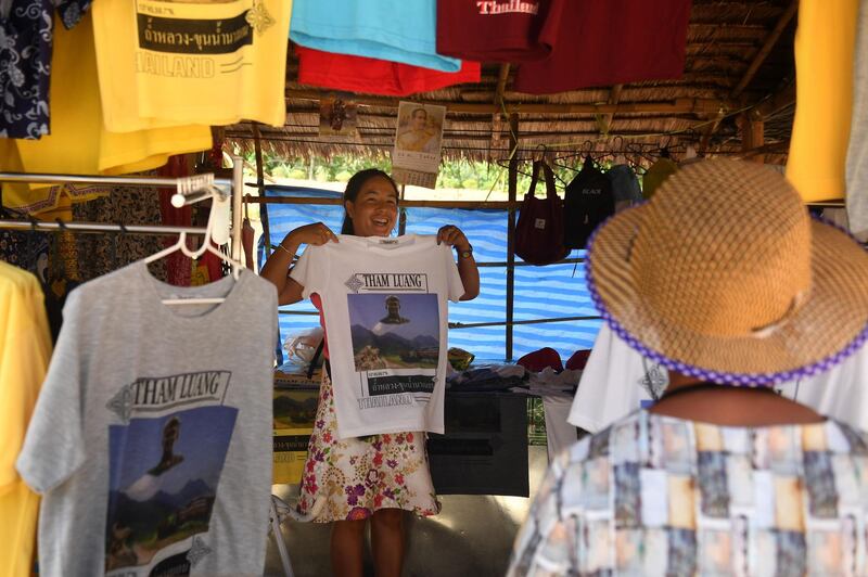A visitor buying a souvenir T-shirt on the road leading to the Tham Luang cave. AFP