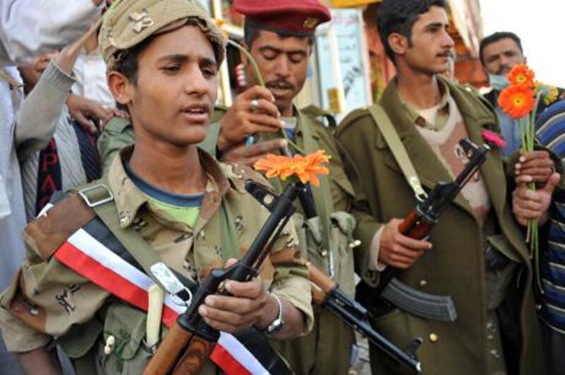 epa02649046 Yemeni army soldiers hold flowers they received from anti-government protesters demanding the ouster of Yemeni President Ali Abdullah Saleh, during protest in the capital Sanaía, Yemen, 23 March 2011. According to media sources, Yemen's parliament on 23 March voted in support of imposing the emergency law  for 30 days, a motion requested by President Ali Abdullah Saleh in the midst of ongoing anti-government protests. The emergency law suspends the country's constitution, bans protests, and allows for arbitrary arrests and censorship.  EPA/YAHYA ARHAB *** Local Caption ***  02649046.jpg