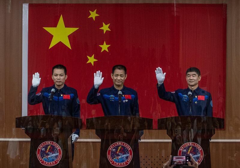 JIUQUAN, CHINA - JUNE 16: (L-R) Chinese astronauts Tang Hongbo, Nie Haisheng, and Liu Boming from China's Manned Space Agency wave from behind a glass room during a press conference on June 16, 2021 in Jiuquan, Gansu province, China. The crew of the Shenzhou-12 spacecraft will be carried by a Long March-2F rocket, set to launch to the space station China is building, from the Gobi Desert on June 17, marking the country's manned mission in nearly five years. (Photo by Kevin Frayer/Getty Images)