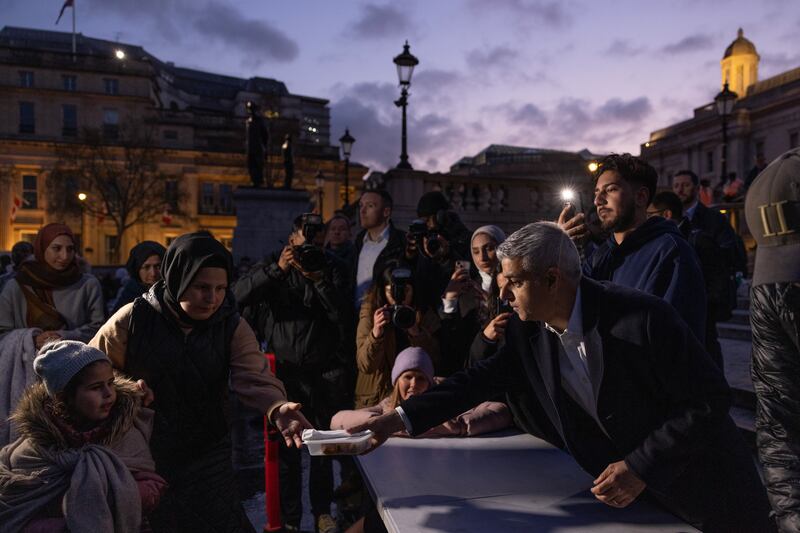 Mr Khan, right, hands out food for iftar in Trafalgar Square. Getty 