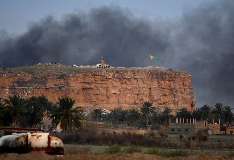 Smoke rising over the village of Baghouz in the eastern Syrian province of Deir Ezzor, with the flags of the Kurdish People's Protection Units (Yellow) and Women's Protection Units (Green) seen flying at one of their positions in the background.  AFP