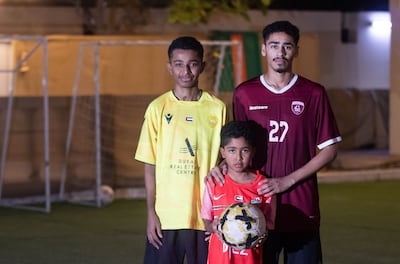 Juma Mubarak Al Ali, in the yellow shirt, plays football with brothers Ahmed and Humaid at their home. Leslie Pableo for The National

