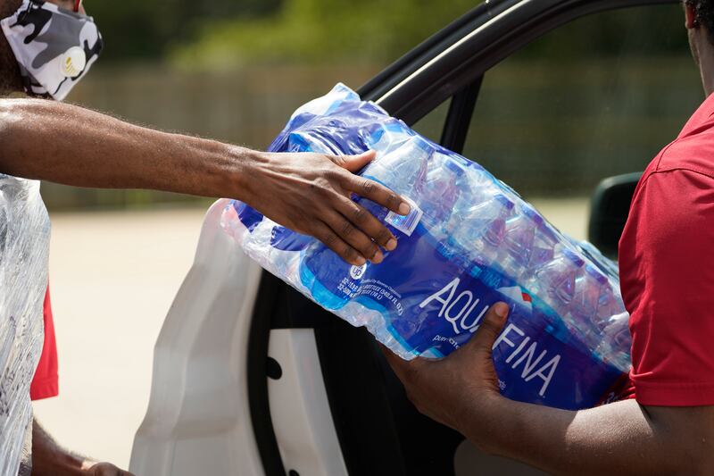 Salvation Army volunteers pass a case of water to a waiting driver in Jackson. AP