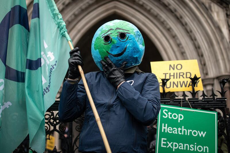 LONDON, ENGLAND - FEBRUARY 27: A man wearing a smiling earth mask celebrates as he stands with fellow campaigners outside the Royal Courts of Justice following the announcement ruling against the controversial third runway for Heathrow airport on February 27, 2020 in London, England.  Critics of the plans took the case to the court of appeal, claiming that the developments did not take into account climate change commitments. (Photo by Leon Neal/Getty Images)