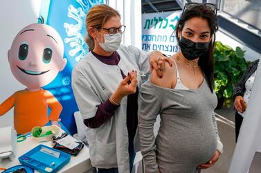 A health worker administers a dose of the Pfizer-BioNtech COVID-19 coronavirus vaccine to a pregnant woman at Clalit Health Services, in Israel's Mediterranean coastal city of Tel Aviv on January 23, 2021. Israel began administering novel coronavirus vaccines to teenagers as it pushed ahead with its inoculation drive, with a quarter of the population now vaccinated, health officials said. / AFP / JACK GUEZ