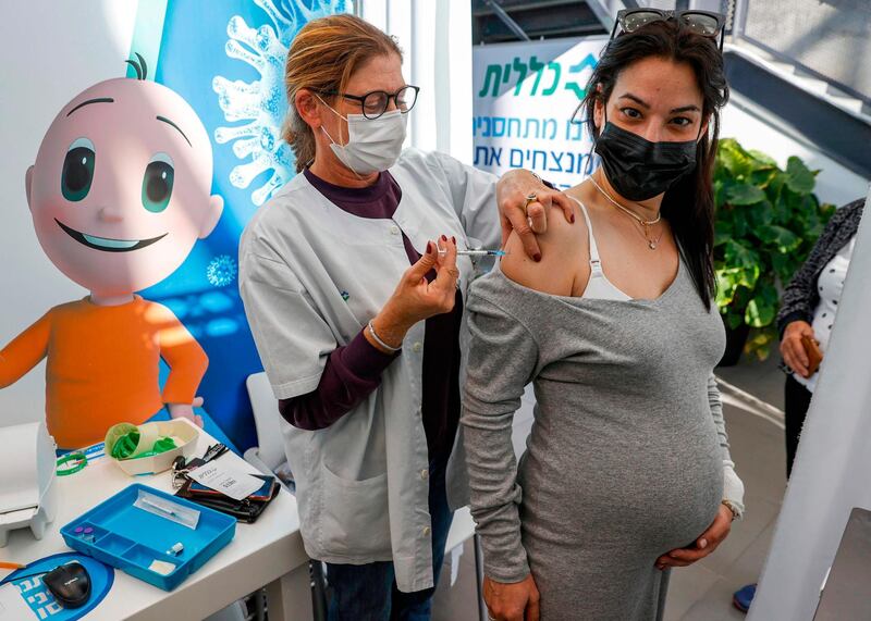 A health worker administers a dose of the Pfizer-BioNtech COVID-19 coronavirus vaccine to a pregnant woman at Clalit Health Services, in Israel's Mediterranean coastal city of Tel Aviv on January 23, 2021.  Israel began administering novel coronavirus vaccines to teenagers as it pushed ahead with its inoculation drive, with a quarter of the population now vaccinated, health officials said. / AFP / JACK GUEZ
