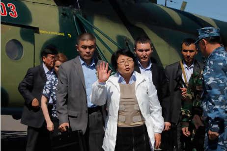 Kyrgyzstan's interim government leader Rosa Otunbayeva, centre, waves after landing by military helicopter on the central square in the southern Kyrgyz city of Osh, Kyrgyzstan, on Friday, June 18, 2010. She is vowing to work for the return of refugees who fled deadly ethnic violence there by the hundreds of thousands.