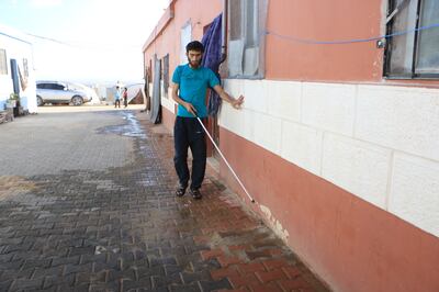 Ahmed Al Hamid walks alone to his house, touching the patterns on the wall. Abd Almajed Alkarh / The National
