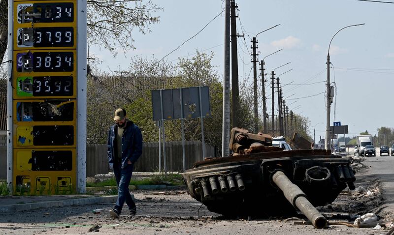 A Ukrainian man walks past the turret of a Russian tank next to a destroyed petrol station in the village of Skybyn, north-east of Kyiv. AFP