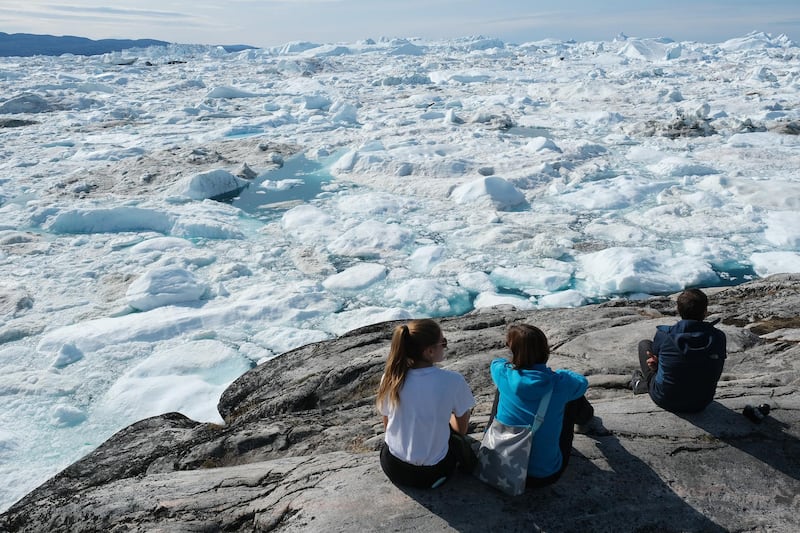 ILULISSAT, GREENLAND - JULY 30: Visitors look out onto free-floating ice jammed into the Ilulissat Icefjord during unseasonably warm weather on July 30, 2019 near Ilulissat, Greenland. The Sahara heat wave that recently sent temperatures to record levels in parts of Europe is arriving in Greenland. Climate change is having a profound effect in Greenland, where over the last several decades summers have become longer and the rate that glaciers and the Greenland ice cap are retreating has accelerated.   (Photo by Sean Gallup/Getty Images)