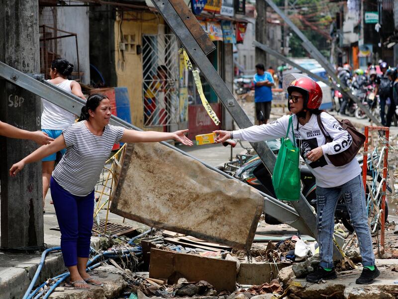 A Filipino motorcycle rider hands over a box of goods as part of the relief operation. EPA