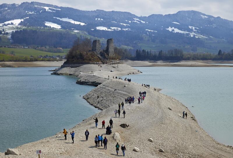 People walk to the ruins of Ogoz castle on Lake Gruyere, Pont-en-Ogoz, Switzerland. Reuters