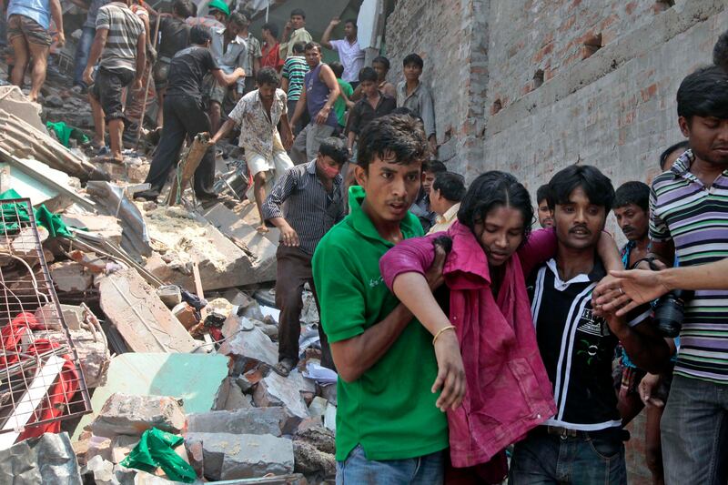 Rescuers assist an injured woman after an eight-story building housing several garment factories collapsed in Savar, near Dhaka, Bangladesh, Wednesday, April 24, 2013. Dozens were killed and many more are feared trapped in the rubble. (AP Photo/ A.M. Ahad) *** Local Caption ***  Bangladesh Building Collapse.JPEG-057a6.jpg
