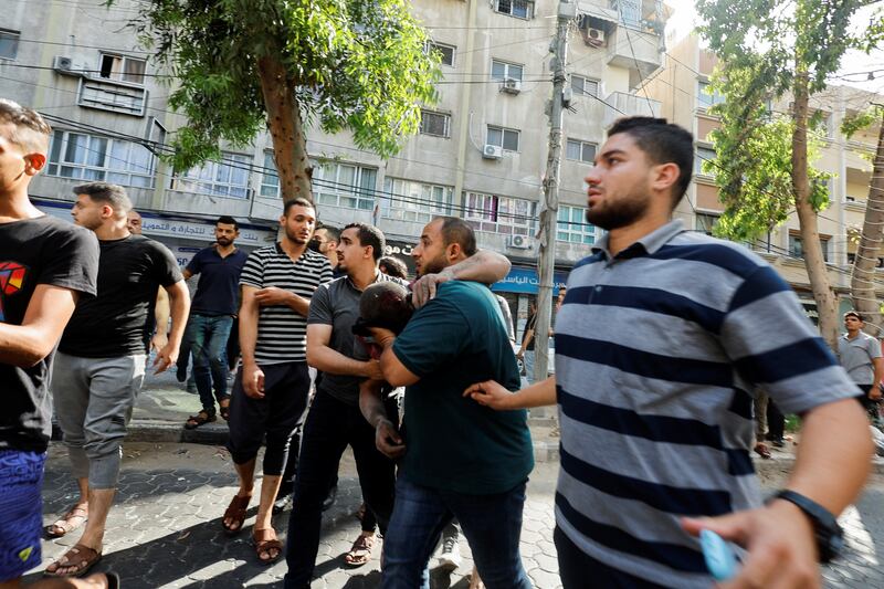 People assist an injured person after the air strike in Gaza city. Reuters