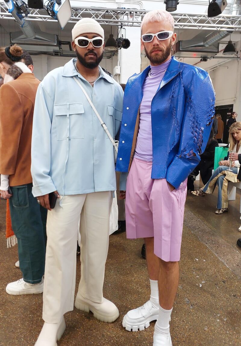 Two men at the J E Cai show, in East London, one dressed in pastels and the other in blue and pink.  