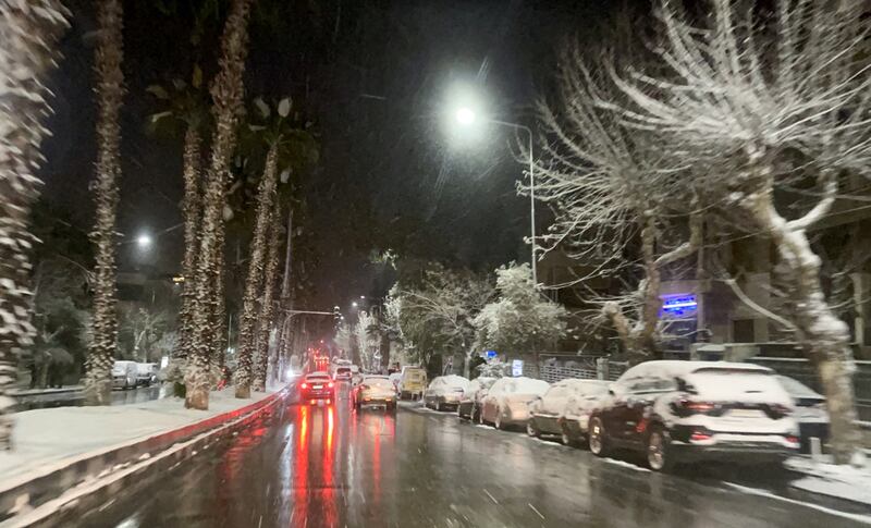 Syrians drive their cars on a street as snow falls over Damascus. AFP