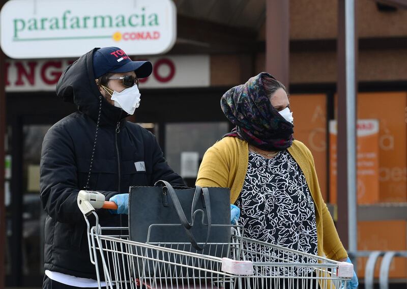 Residents wearing respiratory mask push their cart as they go to shop in a supermarket on February 23, 2020 in the small Italian town of Casalpusterlengo, under the shadow of a new coronavirus outbreak, as Italy took drastic containment steps as worldwide fears over the epidemic spiralled.   / AFP / Miguel MEDINA
