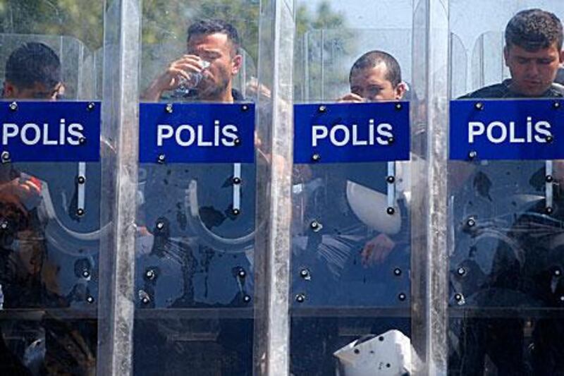 Turkish policemen have a drink while guarding the entrance of Gezi Park near Taksim Square in Istanbul today.