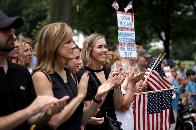 People applaud for the family of the late Senator John McCain as they leave the Vietnam Veterans Memorial following a wreath laying ceremony.  Getty Images / AFP