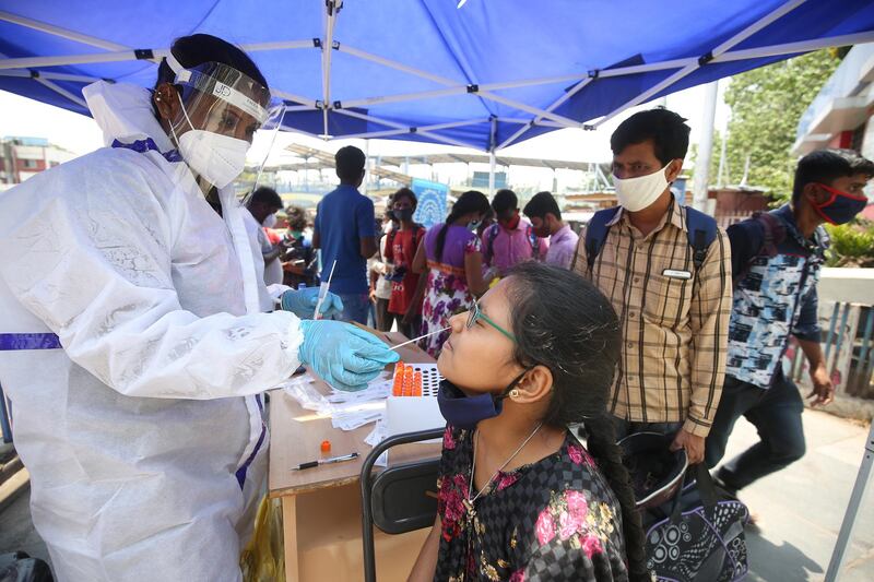 A girl undergoes a swab test at a bus stop in Bangalore, India, on April 7, 2021. EPA